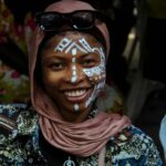 Portrait of a smiling woman with traditional face paint, captured at a cultural event in Nigeria.