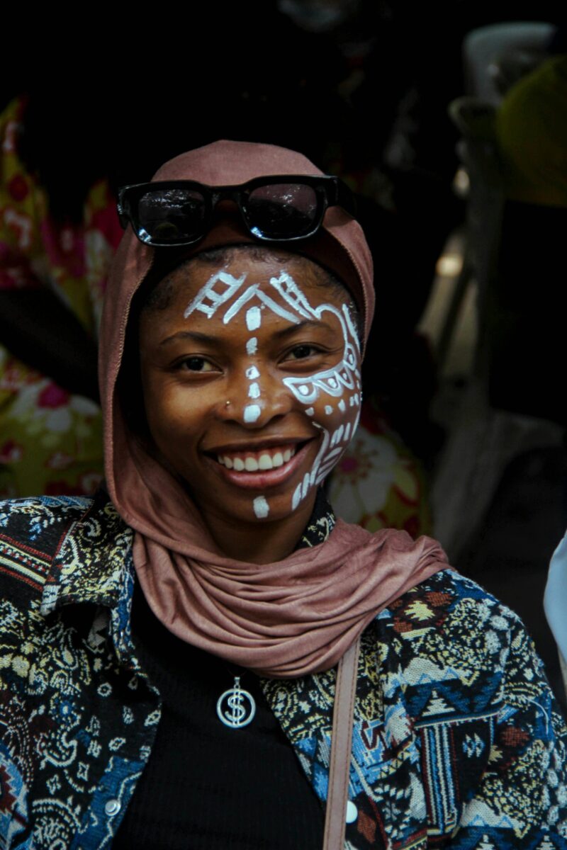 Portrait of a smiling woman with traditional face paint, captured at a cultural event in Nigeria.