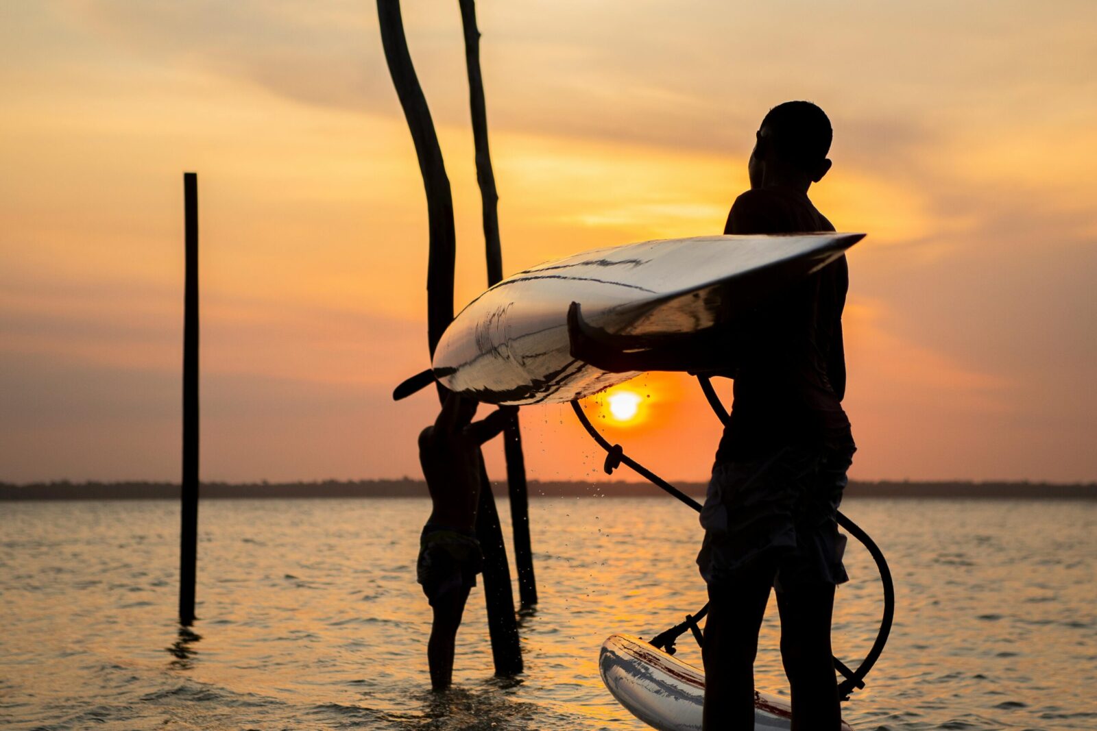 Silhouette of people paddleboarding at sunset in Belém, Brazil's stunning waterscape.